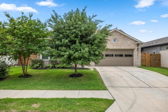 view of property hidden behind natural elements featuring an attached garage, driveway, and brick siding