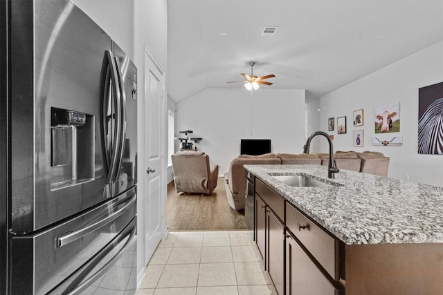 518 Algaroba Loop, Buda, TX 78610 - kitchen with stainless steel fridge, a sink, light stone counters, an island with sink, and ceiling fan