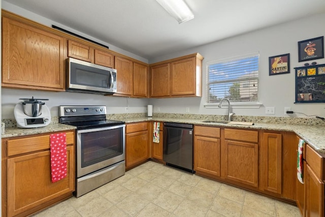 1320 Anna Palm Way, Round Rock, TX 78665 - kitchen featuring appliances with stainless steel finishes, brown cabinetry, light stone counters, and light floors