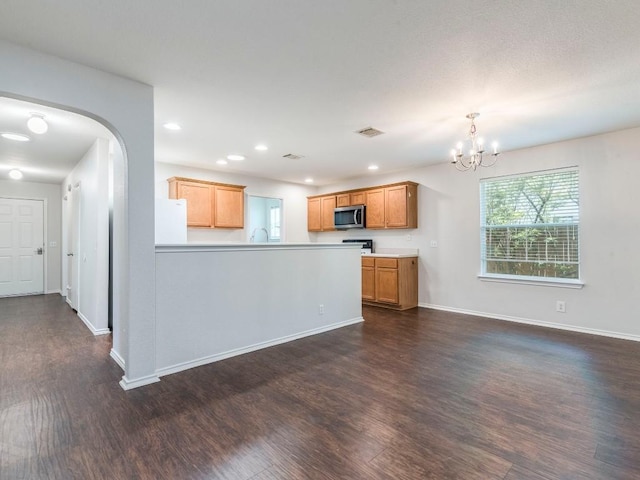 131 Ames Cv, Kyle, TX 78640 - kitchen with stainless steel microwave, freestanding refrigerator, dark wood-style flooring, a chandelier, and light countertops