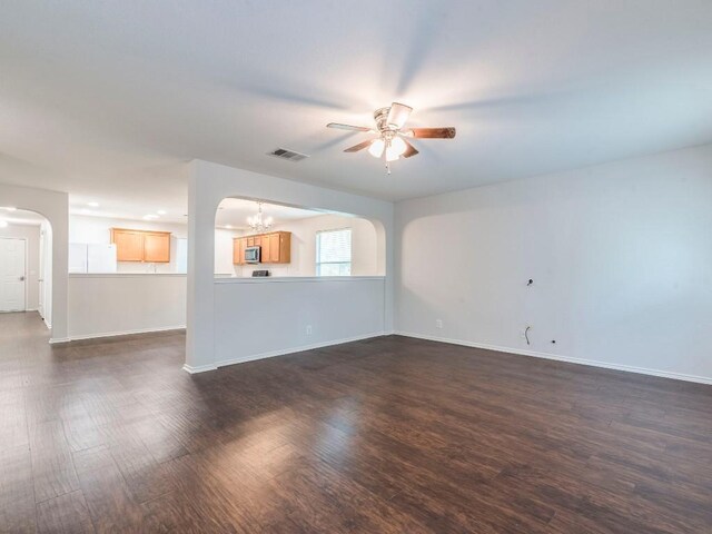 131 Ames Cv, Kyle, TX 78640 - unfurnished living room featuring arched walkways, a ceiling fan, dark wood-type flooring, and a chandelier