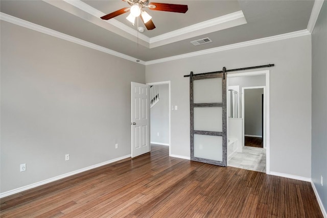 205 Talon Grasp Trl, Leander, TX 78641 - unfurnished room featuring a barn door, a ceiling fan, a raised ceiling, wood finished floors, and crown molding