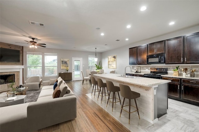 205 Talon Grasp Trl, Leander, TX 78641 - kitchen featuring black appliances, open floor plan, a breakfast bar, a kitchen island with sink, and recessed lighting