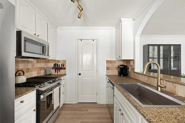 2812 Sissinghurst Dr, Austin, TX 78745 - kitchen with appliances with stainless steel finishes, a sink, light wood-style floors, decorative backsplash, and arched walkways