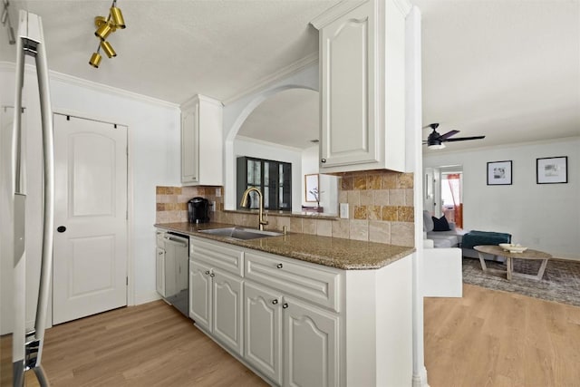 2812 Sissinghurst Dr, Austin, TX 78745 - kitchen featuring stainless steel dishwasher, a sink, a ceiling fan, light wood-style floors, and ornamental molding