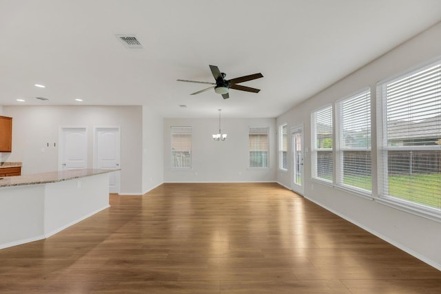 unfurnished living room with a ceiling fan, wood finished floors, a chandelier, recessed lighting, and baseboards
