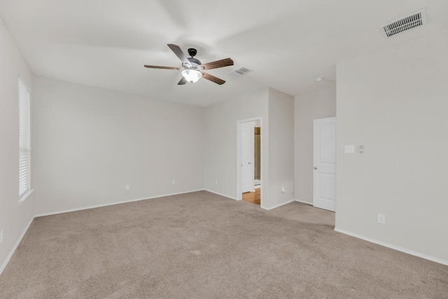 carpeted spare room featuring ceiling fan and baseboards