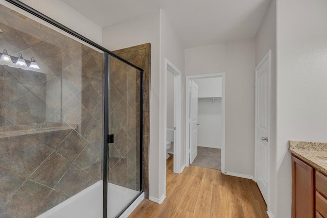 full bathroom with wood finished floors, a shower stall, toilet, and vanity