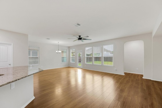 unfurnished living room featuring a ceiling fan, wood finished floors, a chandelier, and baseboards