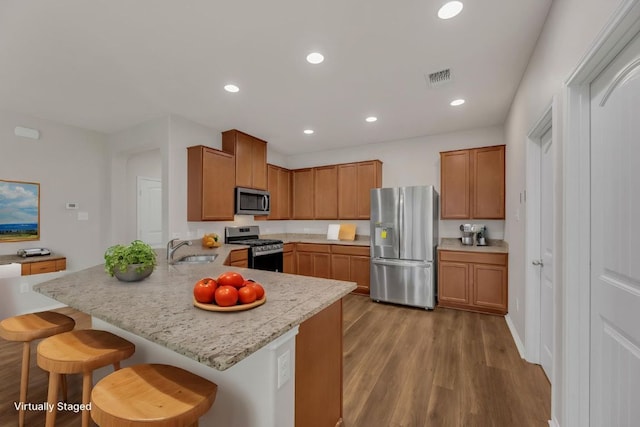 5928 Pescia St, Round Rock, TX 78665 - kitchen with stainless steel appliances, a breakfast bar, wood finished floors, a peninsula, and recessed lighting