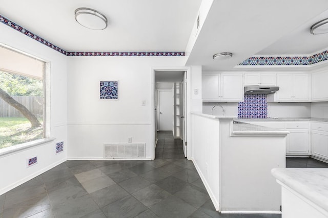 4007 Edgerock Dr, Austin, TX 78731 - kitchen with under cabinet range hood, white cabinetry, light countertops, baseboards, and dark tile patterned floors