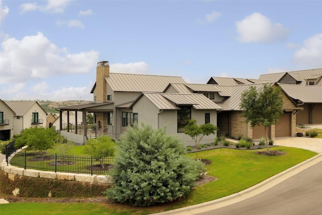 view of front facade with a standing seam roof, a chimney, stucco siding, driveway, and metal roof