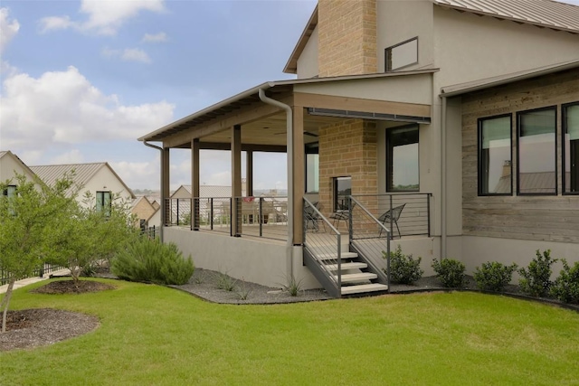 back of property featuring a yard, stucco siding, and stone siding