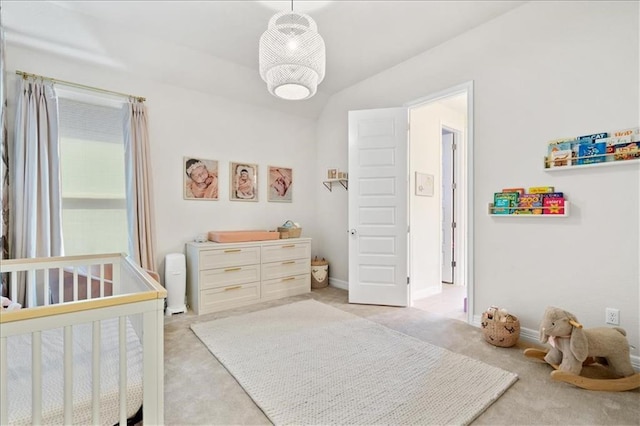 bedroom featuring light colored carpet, a nursery area, lofted ceiling, and baseboards