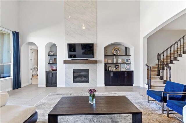 1513 Burr Pkwy, Leander, TX 78641 - tiled living area with built in shelves, a high ceiling, a fireplace, stairway, and baseboards