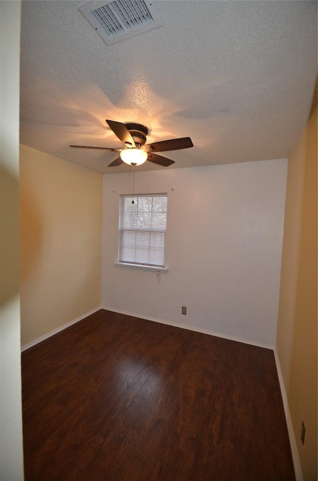 unfurnished room with dark wood finished floors, a ceiling fan, a textured ceiling, and baseboards