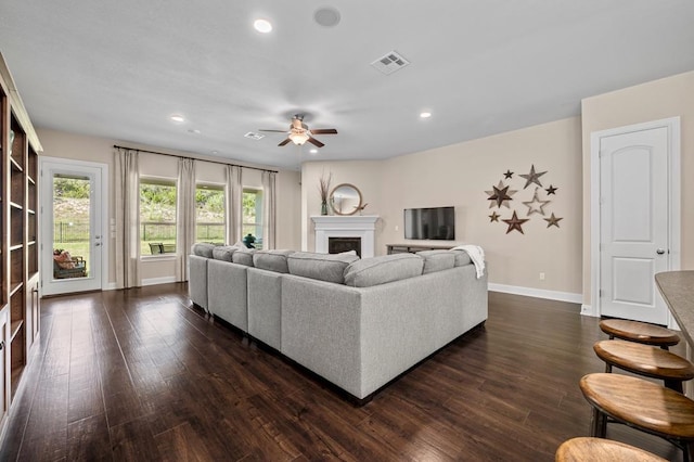living area with a ceiling fan, dark wood-type flooring, baseboards, a fireplace, and recessed lighting