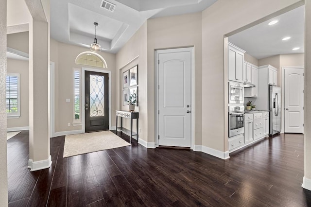 entryway with baseboards, dark wood finished floors, recessed lighting, and a tray ceiling