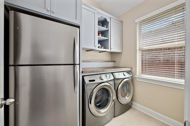 laundry area featuring cabinet space, washing machine and dryer, baseboards, and light tile patterned floors