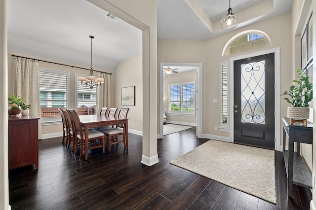 entrance foyer with baseboards, dark wood-style floors, a chandelier, a ceiling fan, and a raised ceiling