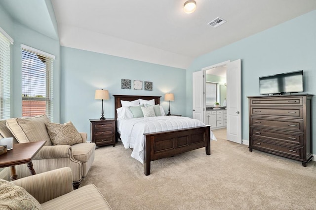 bedroom with light colored carpet and ensuite bath