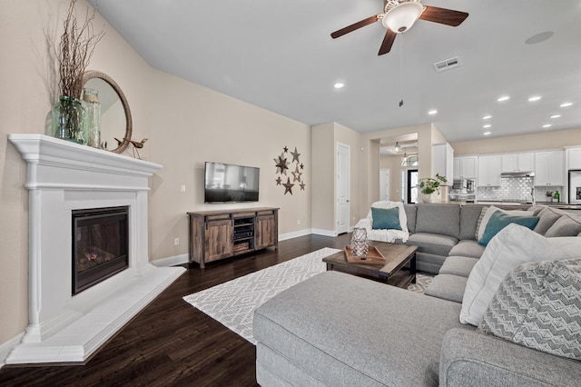 living area featuring ceiling fan, dark wood-style floors, a glass covered fireplace, baseboards, and recessed lighting