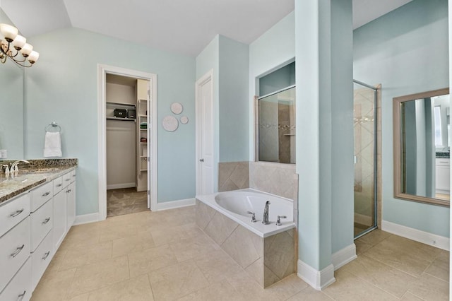 full bathroom featuring a stall shower, vanity, a bath, a spacious closet, and a chandelier
