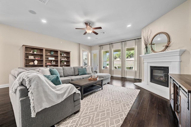 living area with a ceiling fan, dark wood-style floors, a glass covered fireplace, baseboards, and recessed lighting