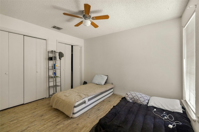 515 Sierra Cv, Round Rock, TX 78664 - bedroom with light wood-style floors, a textured ceiling, two closets, and a ceiling fan