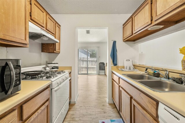515 Sierra Cv, Round Rock, TX 78664 - kitchen featuring white appliances, a sink, under cabinet range hood, a textured ceiling, and light wood finished floors
