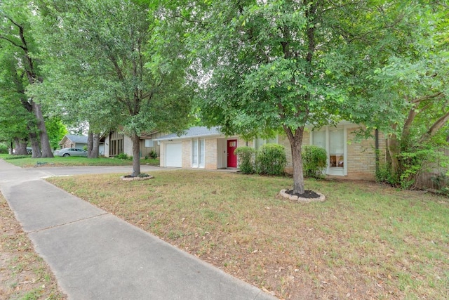 9811 Hansford Dr, Austin, TX 78753 - obstructed view of property featuring brick siding, concrete driveway, an attached garage, and a front lawn