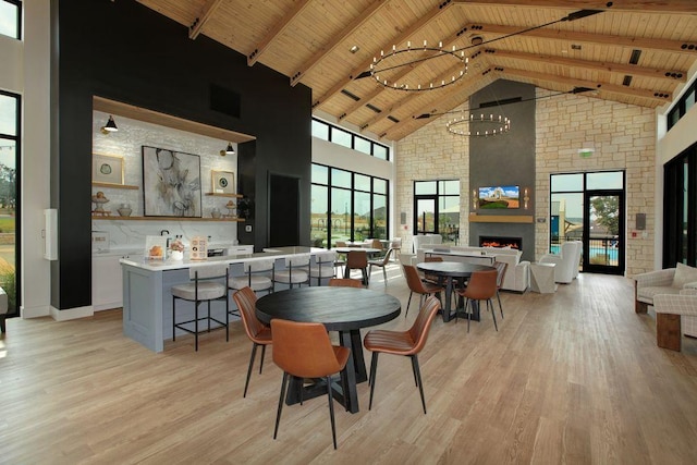 305 Golden Sage Ave, Georgetown, TX 78633 - dining space with high vaulted ceiling, a wood ceiling with exposed beams, light wood-style floors, a large fireplace, and a chandelier