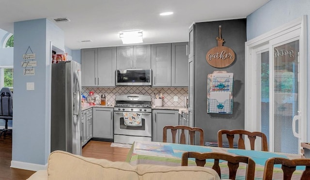 3400 Settlement Dr, Round Rock, TX 78665 - kitchen featuring appliances with stainless steel finishes, gray cabinetry, wood finished floors, tasteful backsplash, and recessed lighting