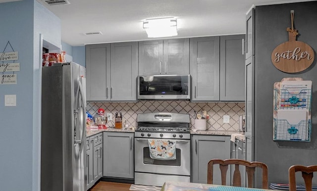 3400 Settlement Dr, Round Rock, TX 78665 - kitchen featuring stainless steel appliances, decorative backsplash, gray cabinetry, and light stone counters