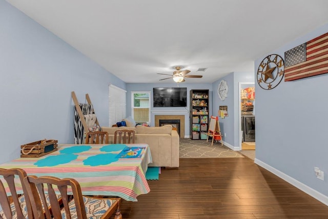 3400 Settlement Dr, Round Rock, TX 78665 - dining room featuring ceiling fan, a fireplace, wood finished floors, and baseboards