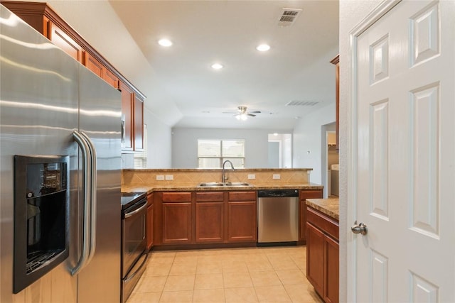 kitchen with appliances with stainless steel finishes, a sink, a peninsula, light tile patterned floors, and a ceiling fan