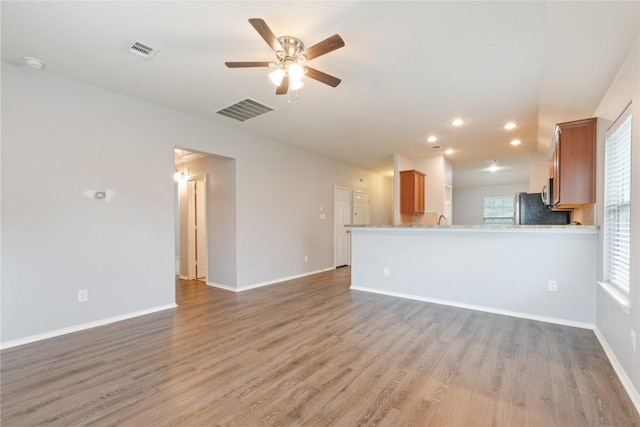 unfurnished living room with ceiling fan, light wood-style flooring, lofted ceiling, baseboards, and recessed lighting