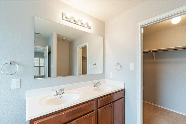 full bathroom with double vanity and a walk in closet