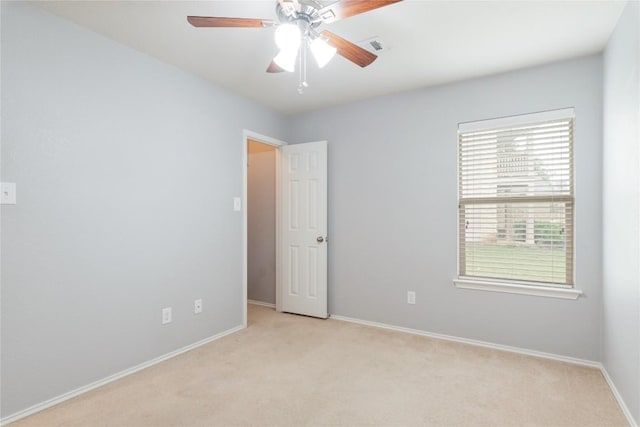 empty room featuring light colored carpet, baseboards, and a ceiling fan