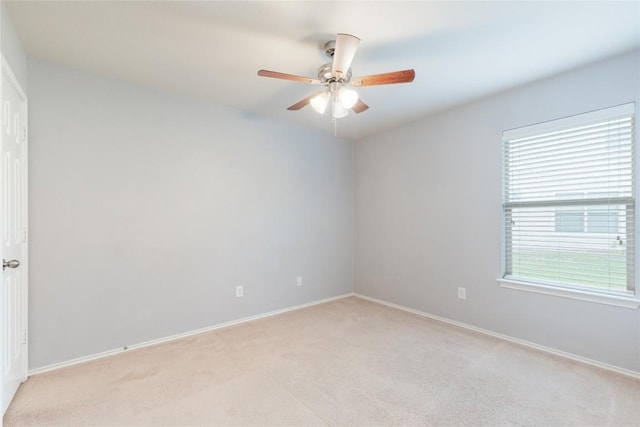 empty room with light colored carpet, ceiling fan, and baseboards