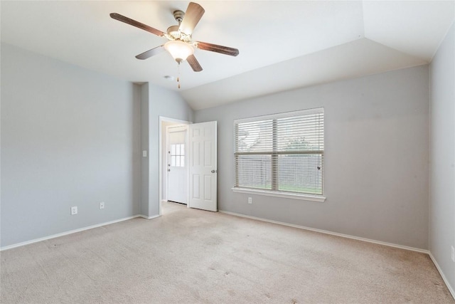 spare room with lofted ceiling, light carpet, baseboards, and a ceiling fan
