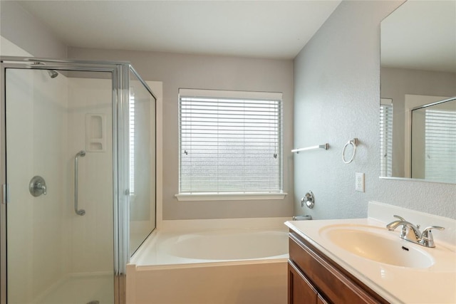 bathroom with a stall shower, vanity, a garden tub, and a textured wall