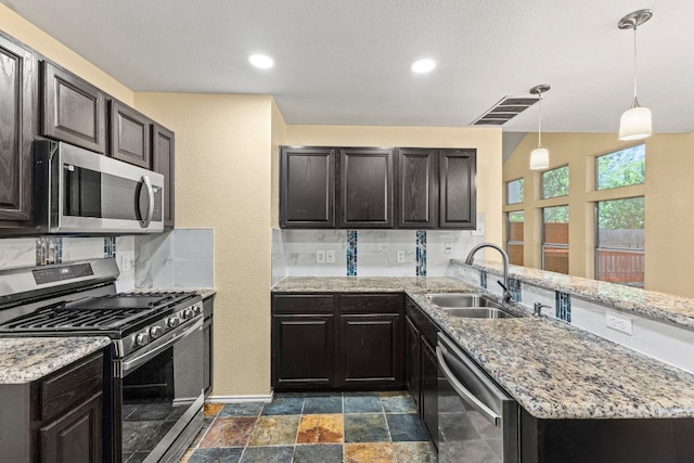 9216 Vigen Cir, Austin, TX 78748 - kitchen with appliances with stainless steel finishes, a sink, a peninsula, baseboards, and light stone countertops