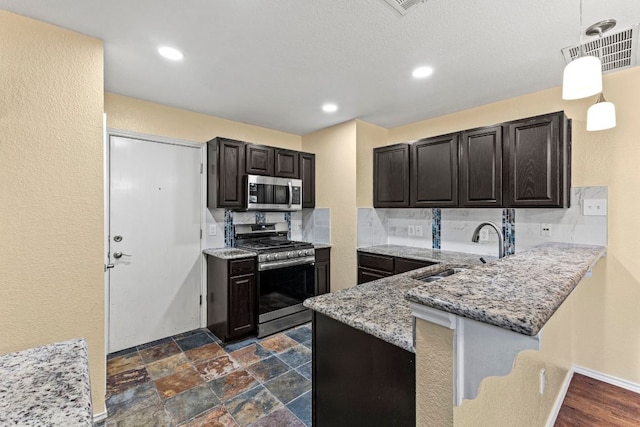 9216 Vigen Cir, Austin, TX 78748 - kitchen featuring appliances with stainless steel finishes, a sink, light stone counters, a peninsula, and decorative light fixtures