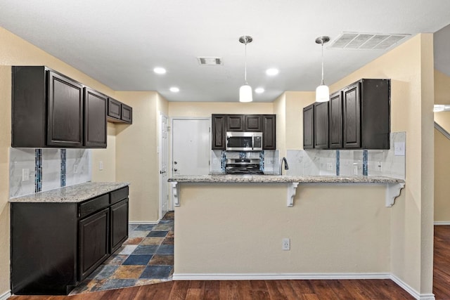 9216 Vigen Cir, Austin, TX 78748 - kitchen with stainless steel appliances, a peninsula, light stone counters, backsplash, and recessed lighting