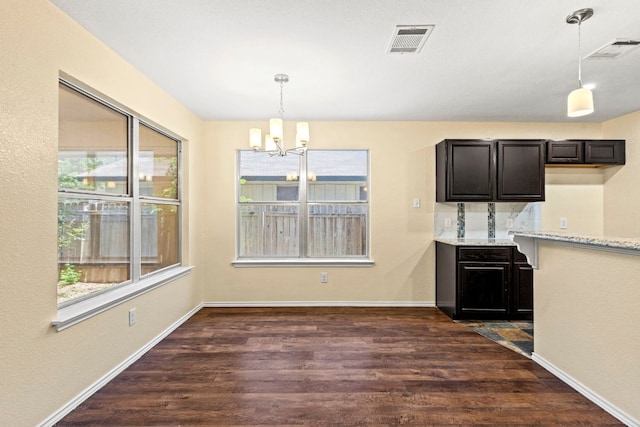 9216 Vigen Cir, Austin, TX 78748 - unfurnished dining area featuring a chandelier, dark wood-type flooring, and baseboards