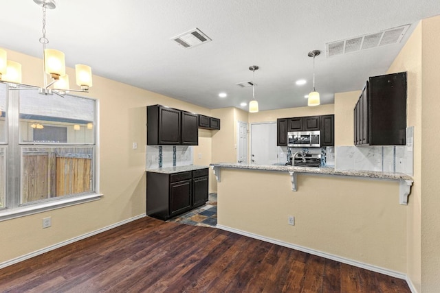 9216 Vigen Cir, Austin, TX 78748 - kitchen with stainless steel microwave, light stone countertops, dark wood finished floors, a peninsula, and baseboards