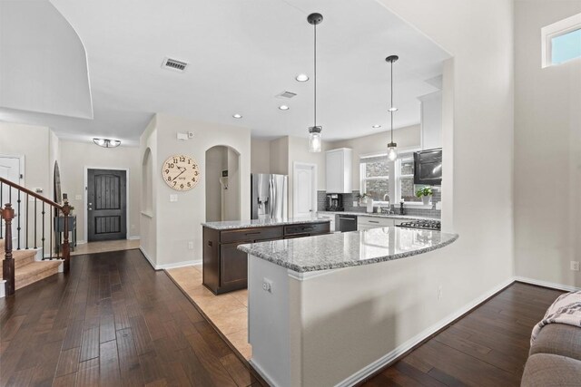 8058 Arezzo Dr, Round Rock, TX 78665 - kitchen featuring stainless steel appliances, a center island, hardwood / wood-style flooring, light stone countertops, and tasteful backsplash