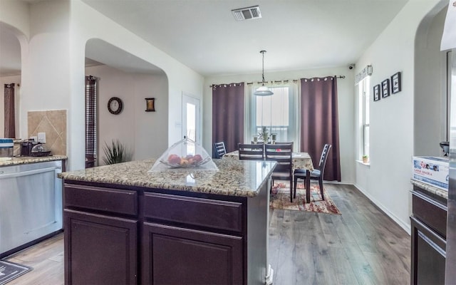 316 Carrington St, Hutto, TX 78634 - kitchen featuring arched walkways, light wood-type flooring, light stone counters, and a kitchen island
