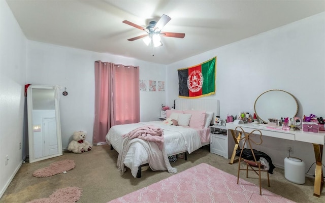 carpeted bedroom with ceiling fan and an office area